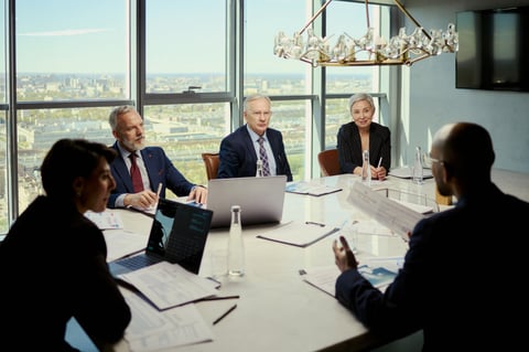 Wide shot of middle aged business team discussing strategy during oil industry meeting in boardroom, reviewing reports and laptop